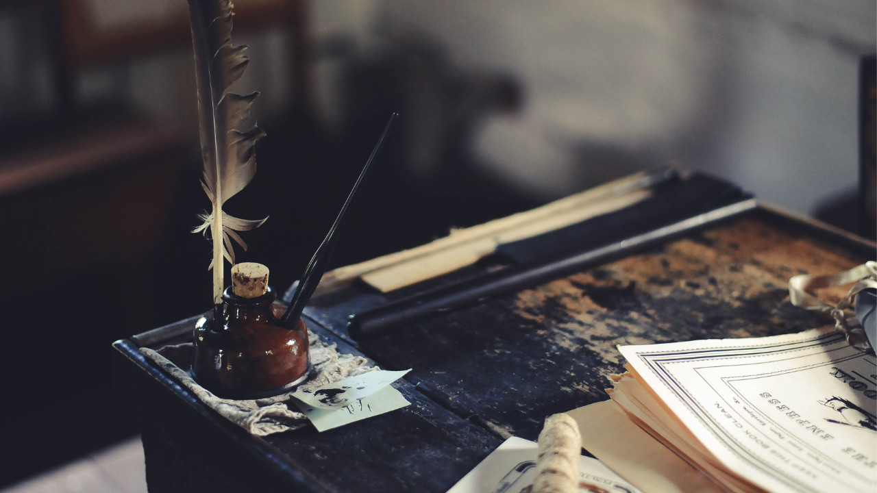 A feather quill in a well of ink