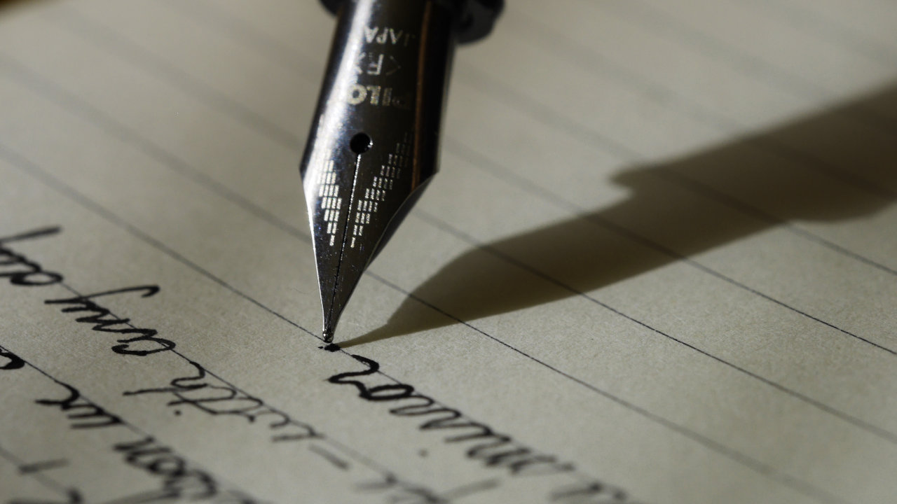 An ink pen writing on lined paper